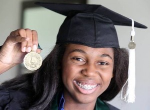 Fourteen year old expecting graduate, Thessalonika Arzu-Embry holds a medal in her cap and gown.